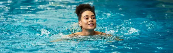 Young woman enjoys a peaceful swim in a luxurious spa, embracing relaxation and rejuvenation. — Stock Photo