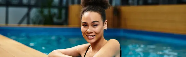 A young african american woman smiles while relaxing in a luxurious spa setting by the water. — Stock Photo