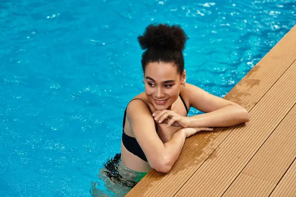 A young chic woman smiles by the pool, enjoying tranquility and self care. — Stock Photo