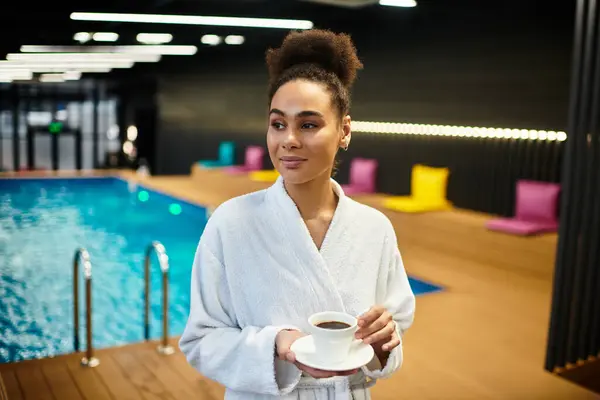 A young African American woman relishes a warm beverage while unwinding by the pool. — Stock Photo