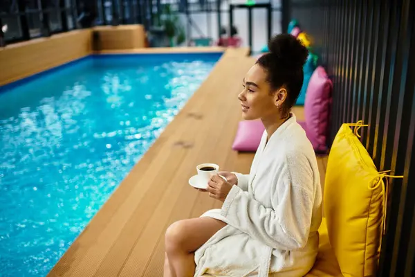 A young chic woman relaxes by the pool, sipping coffee and enjoying a blissful moment. — Stock Photo