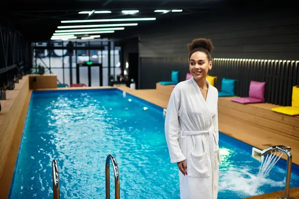 A young woman relaxes in a luxurious spa, radiating joy beside a vibrant blue pool. — Stock Photo