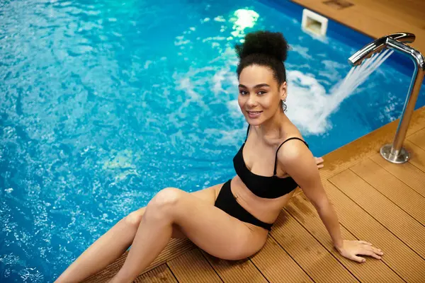 A beautiful young African American woman unwinds by the poolside, embracing peace and relaxation. — Stock Photo