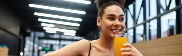 A young African American woman smiles while sipping a refreshing drink in a spa setting. — Stock Photo