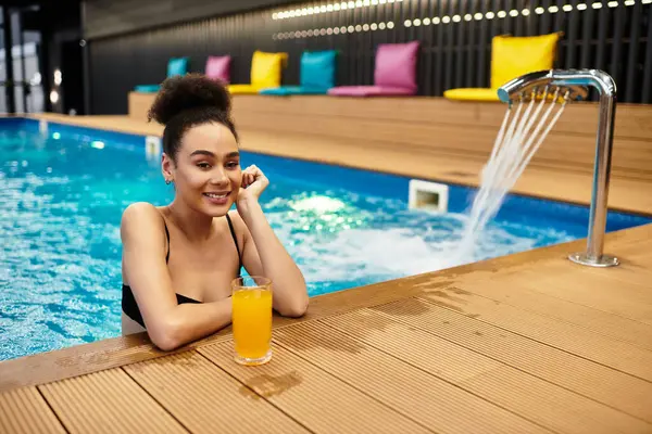 A young woman unwinds by the pool, sipping a vibrant drink, and soaking in serene spa vibes. — Stock Photo
