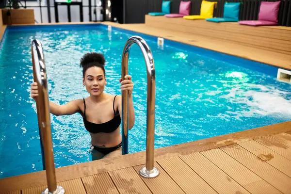 A young african american woman relaxes in a beautiful spa pool, enjoying a moment of tranquility. — Stock Photo