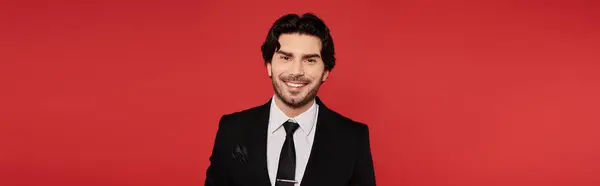 A handsome young man in a sleek suit stands confidently, smiling with charm. — Stock Photo