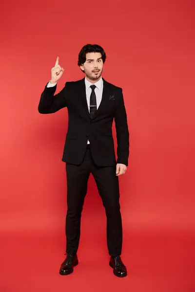 Confident young man in a tailored suit gestures up playfully, radiating charm. — Stock Photo