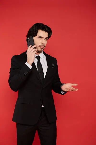 Confident young man wearing a suit speaks on the phone, gesturing expressively in a lively setting. — Stock Photo