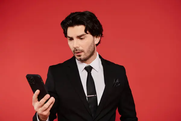 Handsome young man in elegant attire, focused on his smartphone with brunette hair. — Stock Photo
