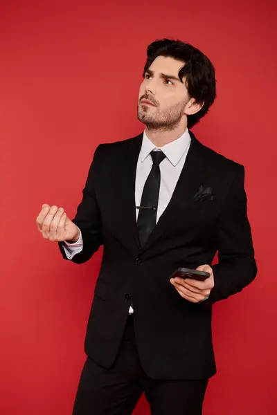 Brunette man in a stylish suit looks thoughtfully up, holding a phone in a bright space. — Stock Photo
