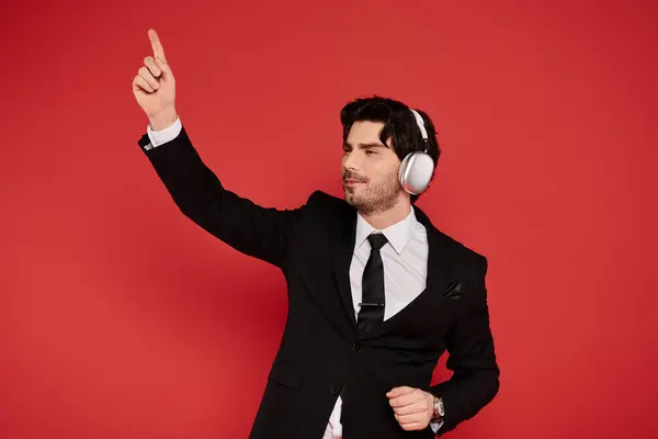 A confident young man in a suit dances energetically with headphones on. — Stock Photo