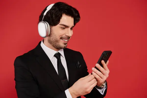 A stylish young man with dark hair listens to music and engages with his smartphone, exuding charm. — Stock Photo
