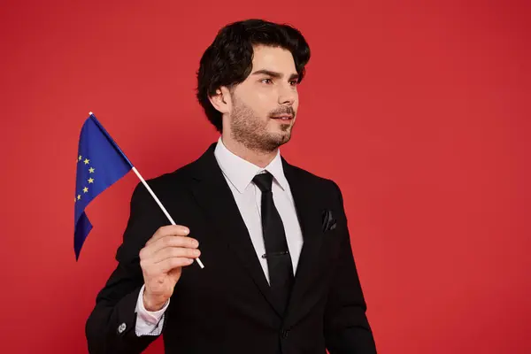 Ein gut gekleideter junger Mann steht selbstbewusst mit einer Europafahne und zeigt seinen Stolz und Stil. — Stockfoto