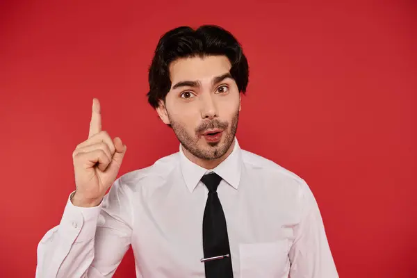 Brunette man dressed in a white shirt and black tie looks amazed while pointing upwards. — Stock Photo