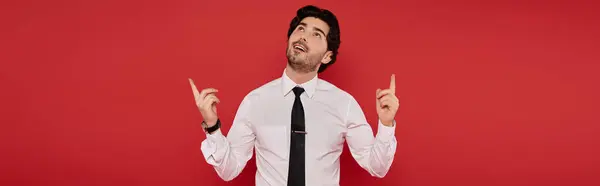 With a confident smile, a young man gestures upward, radiating positivity in a stylish outfit. — Stock Photo