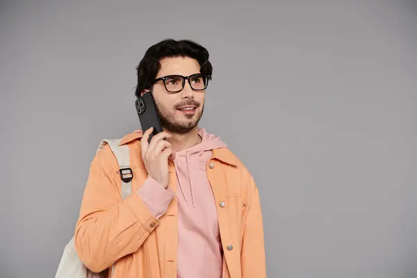 A young man with glasses enjoys a phone conversation while wearing a stylish outfit. — Stock Photo