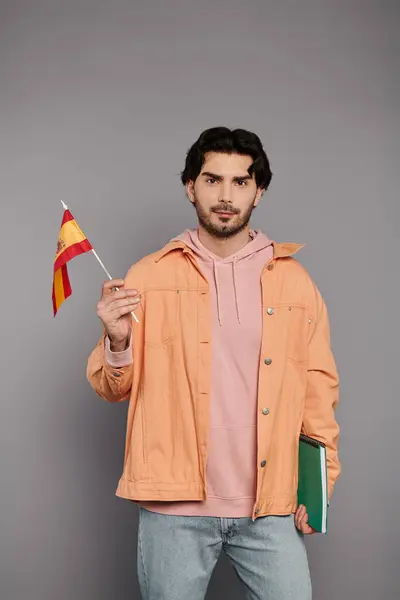 Un giovane in un abito elegante regge orgogliosamente una piccola bandiera, esprimendo gioia e cultura.. — Foto stock