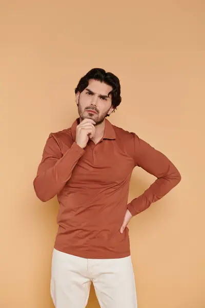 Ein junger brünetter Mann steht selbstbewusst mit nachdenklichem Gesichtsausdruck da und betont seine Gesichtszüge. — Stockfoto