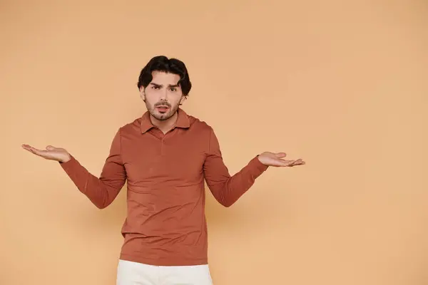 A young handsome man in a rust colored shirt displays a playful expression of curiosity. — Stock Photo