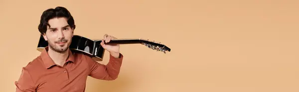 A confident young man carries a guitar on his shoulder in a relaxed vibe. — Stock Photo