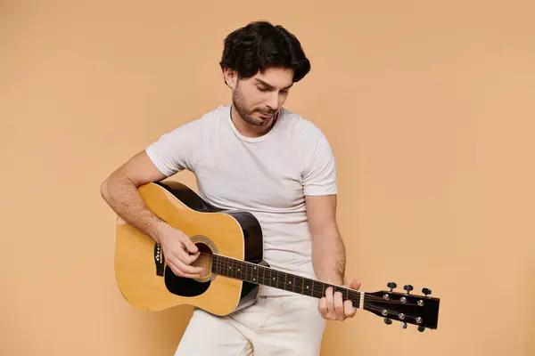 A young man with brunette hair passionately strums his guitar, surrounded by a cozy atmosphere. — Stock Photo