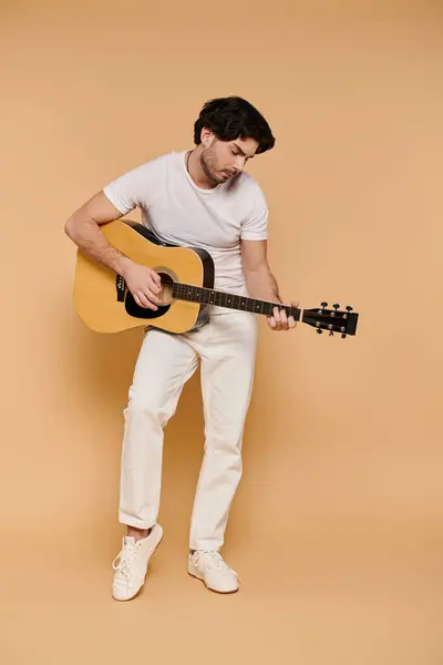 Brunette man intensely plays guitar, pouring creativity into music against warm hues. — Stock Photo
