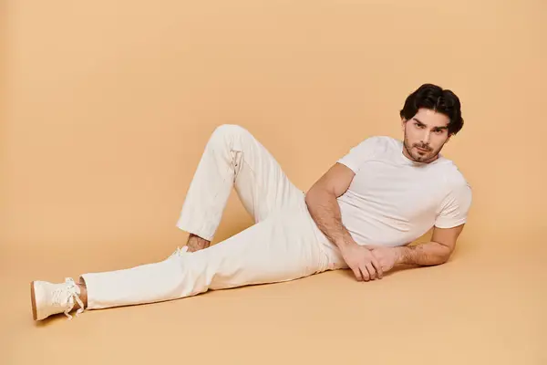 A young brunette man lounges comfortably on a light background, exuding charm and confidence. — Stock Photo