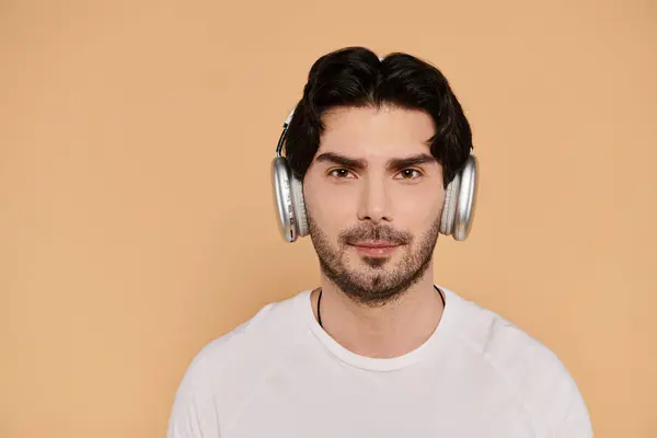 A young handsome man listens to music with headphones, smiling confidently in a cozy atmosphere. — Stock Photo