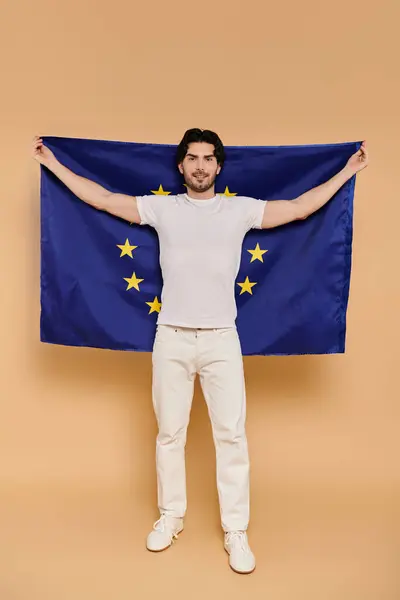 A young man with brunette hair stands confidently, displaying the European Union flag with pride. — Stock Photo