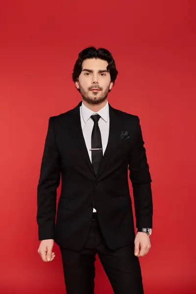 A young man with dark hair stands tall in a black suit, emanating charm and confidence. — Stock Photo