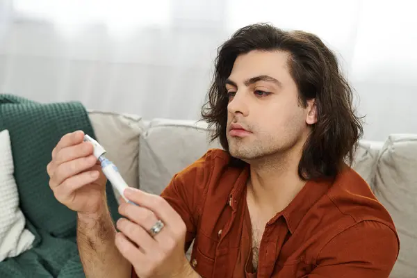 Young man checks his insulin pen while managing diabetes at home in a stylish setting. — Stock Photo