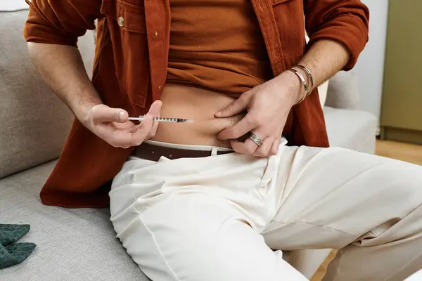 A young man shows his diabetes routine in a chic apartment, focusing on daily health. — Stock Photo
