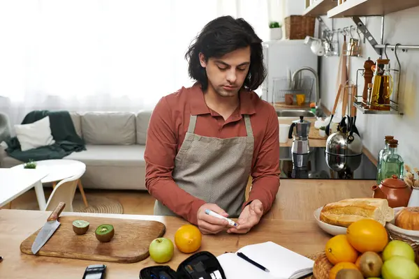 Caucasian man checks blood sugar while preparing fresh fruit in a stylish kitchen. — Stock Photo