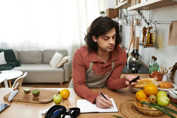 Ein junger Mann mit Diabetes zeichnet seinen Tagesablauf auf, während er zu Hause gesunde Snacks zubereitet. — Stockfoto