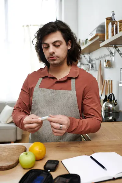 A young man checks his blood sugar level while planning a nutritious meal in his apartment. — Stock Photo
