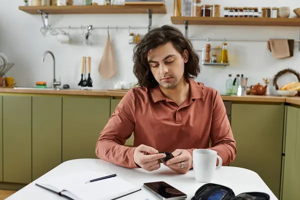 Young man with diabetes checks blood sugar during his morning routine in a sleek kitchen. — Stock Photo