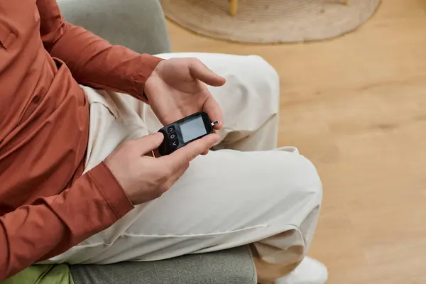 A young man checks his blood sugar levels at home, focusing on his health routine. — Stock Photo