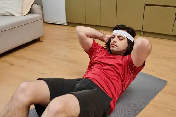 A young man exercises on a fitness mat in his stylish apartment, focusing on his workout routine. — Stock Photo