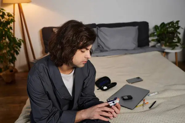 A young man checks his blood sugar levels while relaxing in his stylish apartment. — Stock Photo