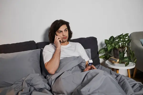 A young man speaks on the phone while managing his diabetes at home, staying connected and healthy. — Stock Photo