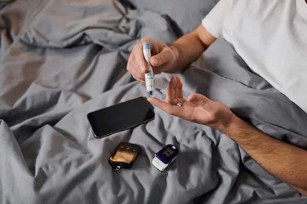A young man checks his blood sugar levels in a modern apartment while managing diabetes. — Stock Photo