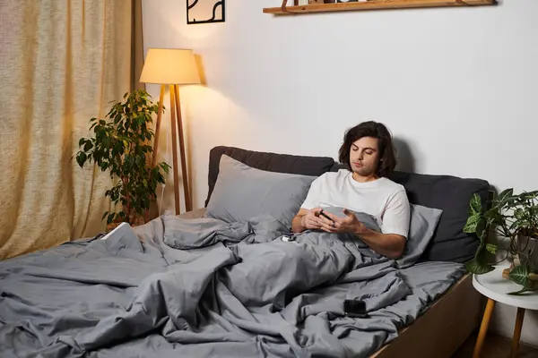 Young man monitors his health and manages diabetes while relaxing in bed at home. — Stock Photo