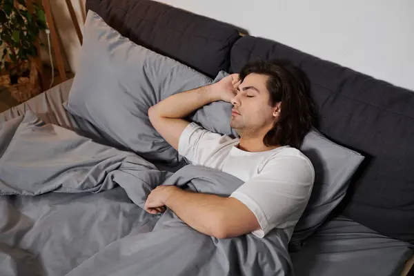 A young man enjoys a peaceful morning at home, resting comfortably in a stylish bed. — Stock Photo