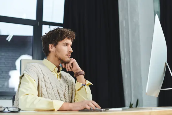 Jeune homme travaille avec diligence à son bureau dans un environnement d'entreprise élégant, habillé intelligemment. — Photo de stock