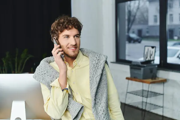 Curly-haired professional in a sweater makes a business call while working in an office. — Stock Photo