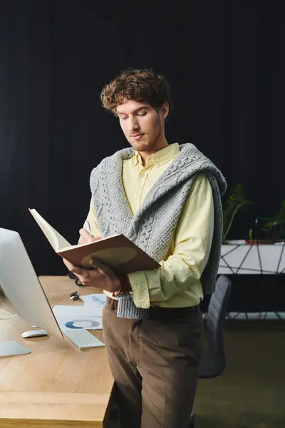 Giovane uomo con i capelli ricci scrive note mentre lavora in un ambiente moderno ufficio aziendale. — Foto stock