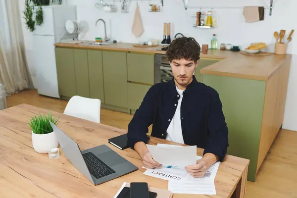 Handsome young man in a shirt reviews documents at his stylish home workspace. — Stock Photo