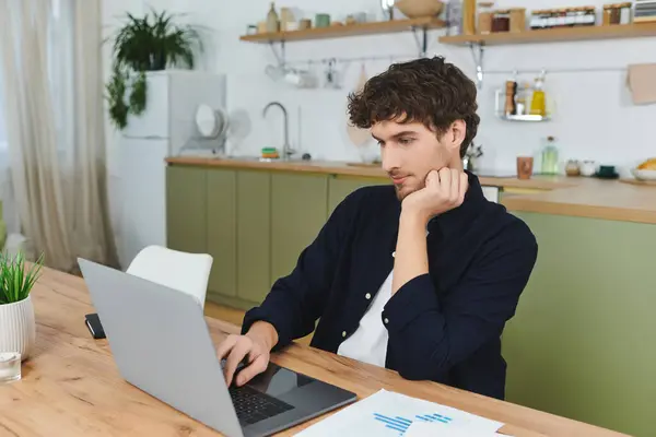 A handsome young man with curly hair is working intently in his stylish apartment. — Stock Photo