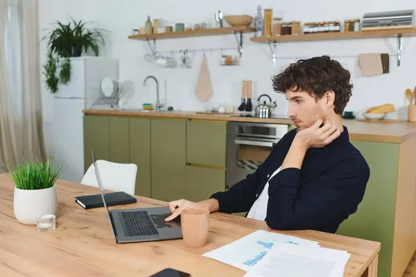 A handsome young man in a shirt focuses on his laptop at home amid modern decor. — Stock Photo